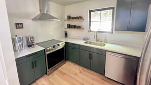 Une cuisine de taille réduite équipée d’une cuisinière, d’un four, d’un évier et d’un lave-vaisselle.