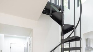 Un intérieur moderne avec un escalier en colimaçon, un plancher en bois et des murs blancs.