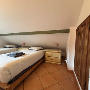 Ein Schlafzimmer mit einem Einzelbett, zwei Nachttischen, einem Beistelltisch und einem Holzschrank.