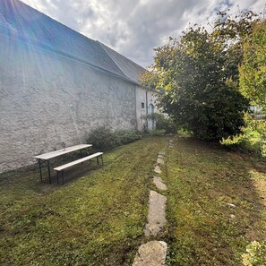 Eine Steinmauer, eine hölzerne Bank und ein Steinweg in einem Garten.