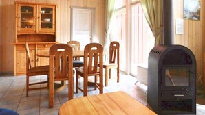A wooden interior with a dining table, chairs, a cabinet, and a wood stove. - Ferienhaus mit Sauna im Ferienpark Mirow (Mirow)