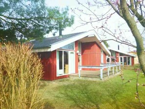 Un bâtiment rouge et blanc avec un toit en pente, un porche couvert et une cour gazonnée.