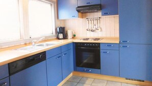 A kitchen with blue cabinets, a dishwasher, an oven, and a coffee maker. - Ferienhaus mit Sauna im Ferienpark Mirow (Mirow)