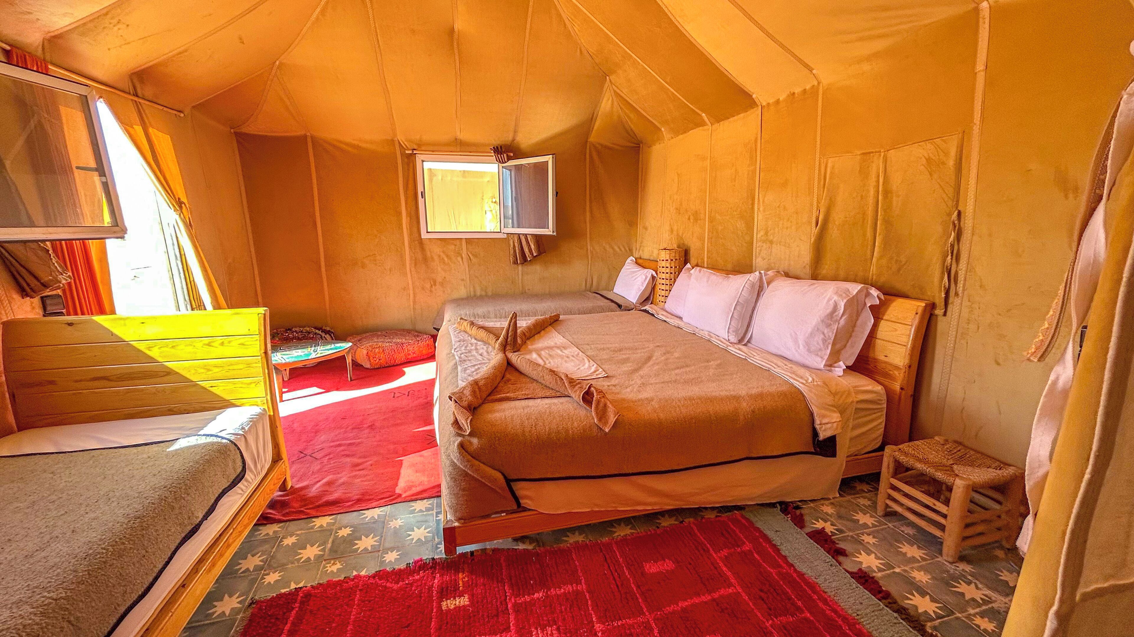 A cozy tented room with a bed, a small table, and a chair.