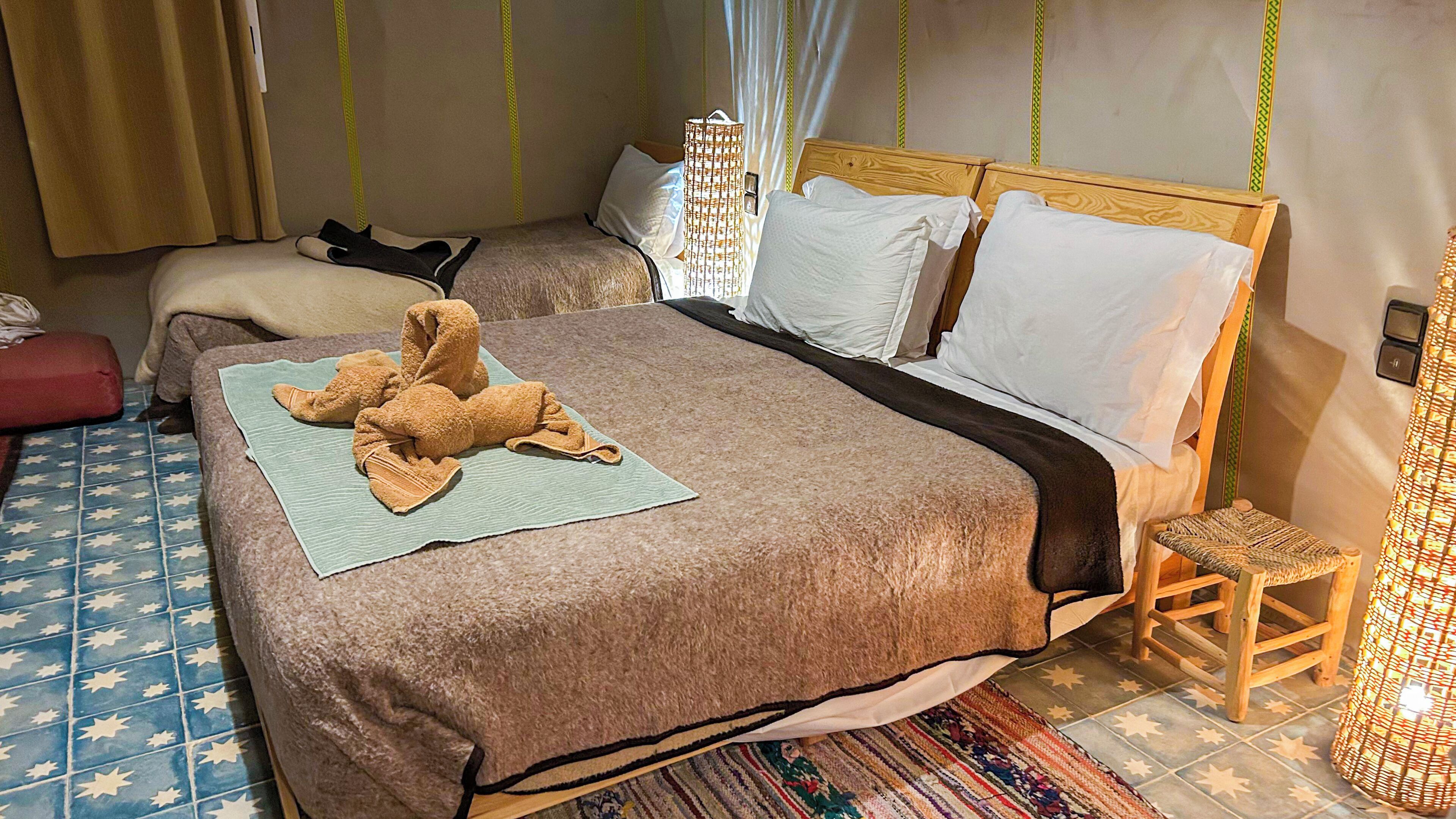 A hotel room with a large bed, a smaller bed, a wooden chair, and a small table.