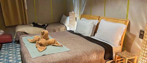 A hotel room with a large bed, a smaller bed, a wooden chair, and a small table.