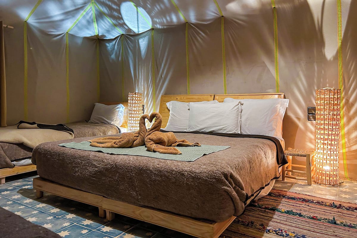 Un dormitorio con una cama grande, dos mesitas de noche y un dosel con tela decorativa.