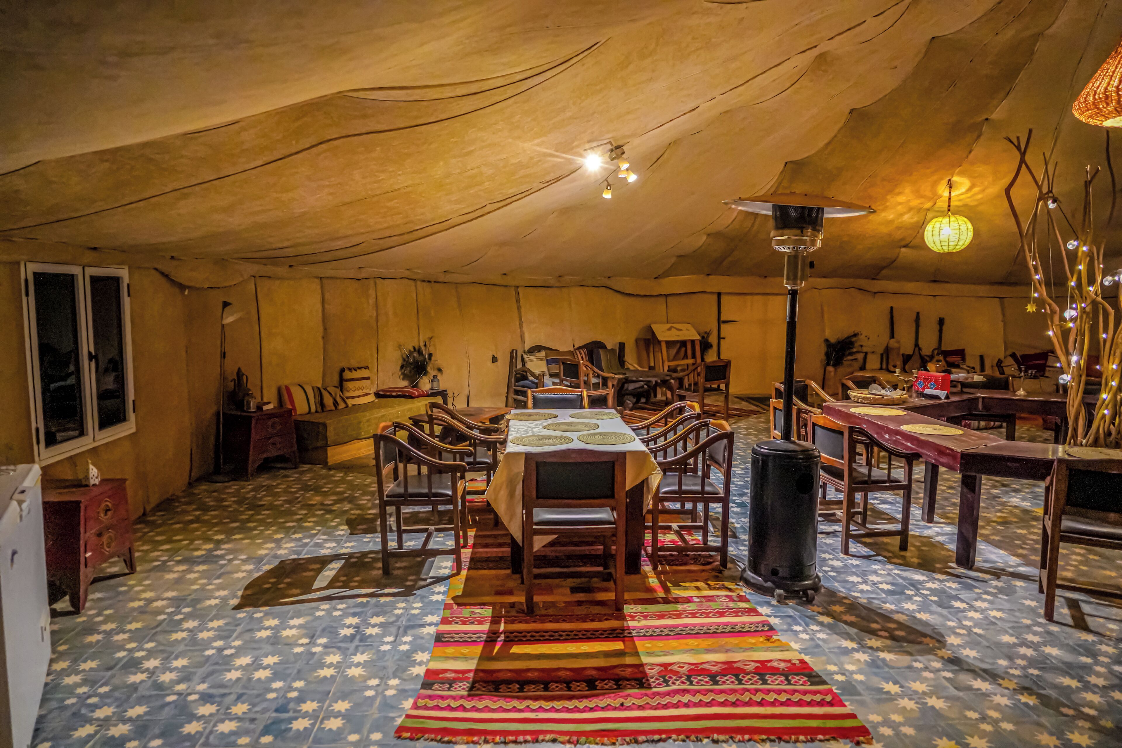 A cozy, well-lit dining area with a large wooden table and chairs, surrounded by various dining tables and chairs.