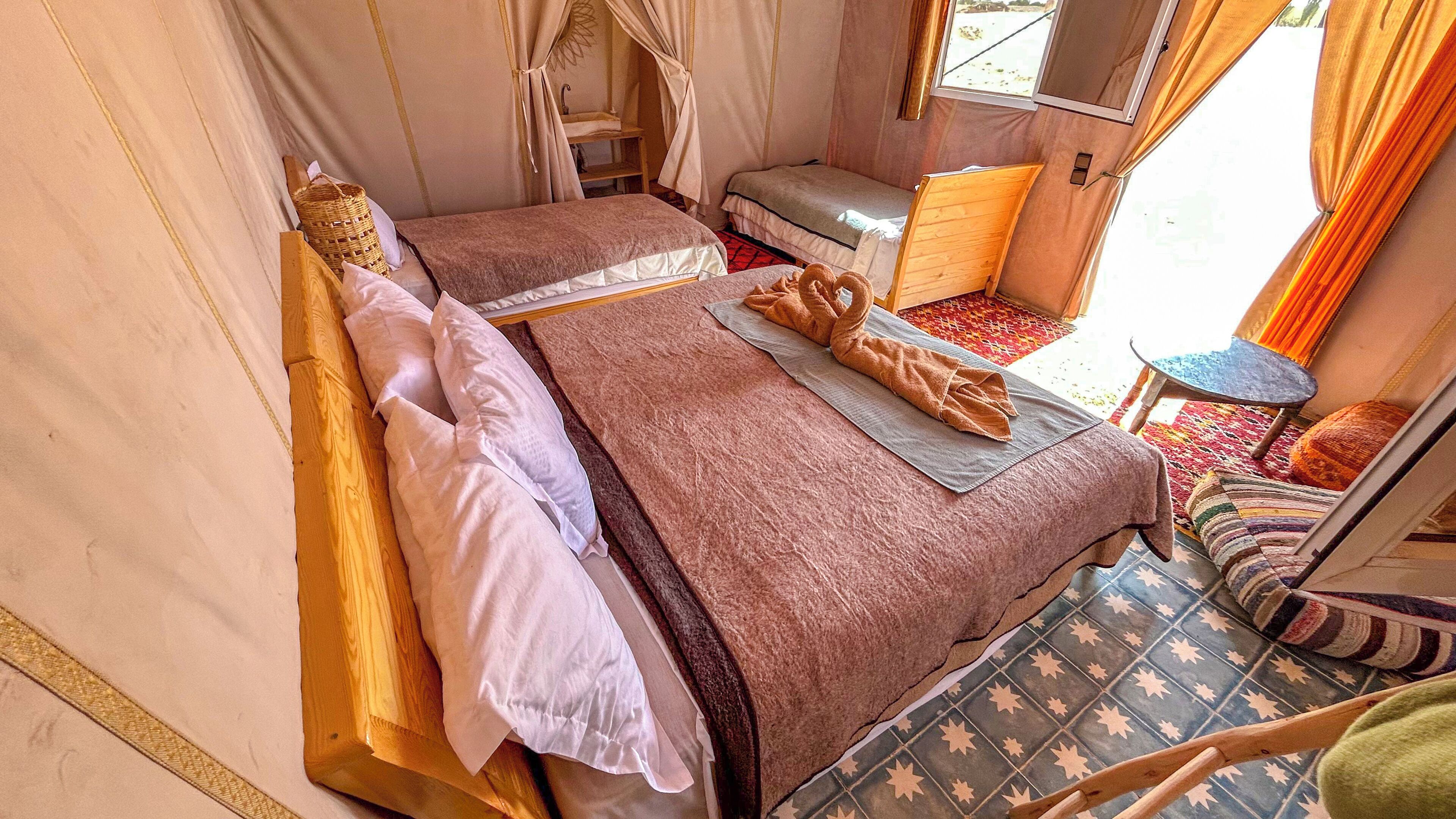 Une chambre avec deux lits, une petite table et une fenêtre.