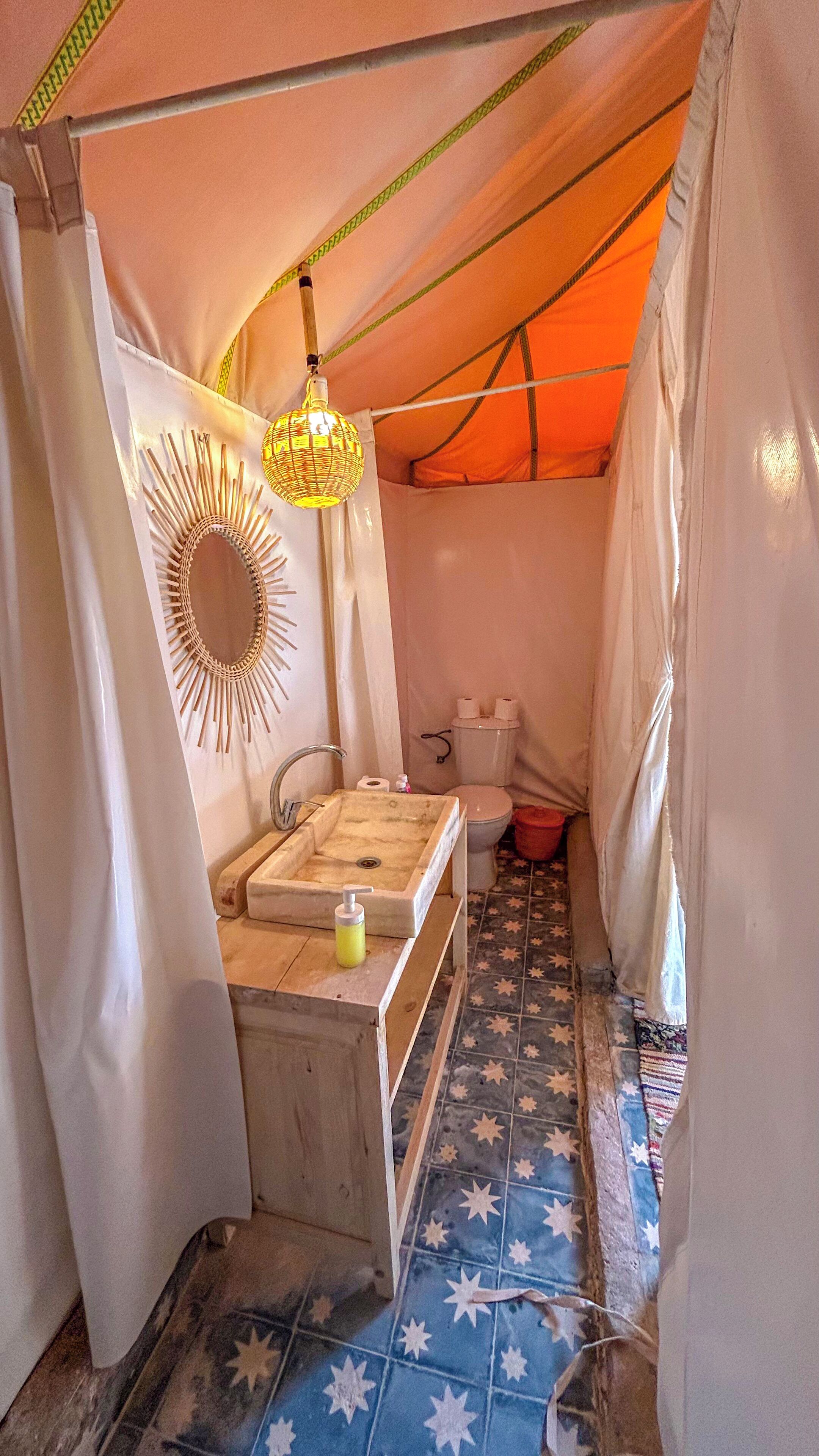 A compact bathroom with a sink, toilet, and hanging light fixture.