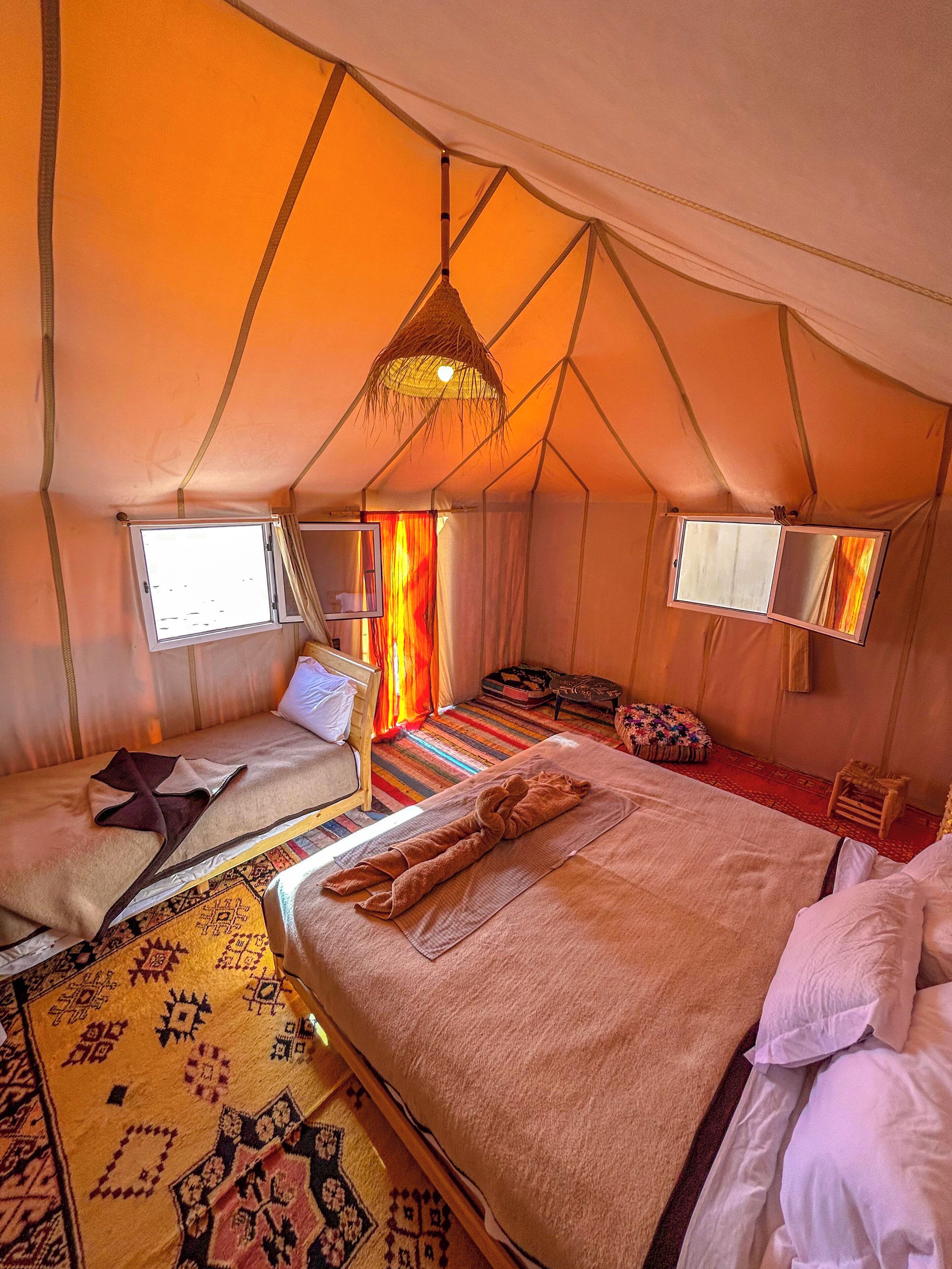 A tented accommodation with a large bed, smaller bed, and a sitting area.