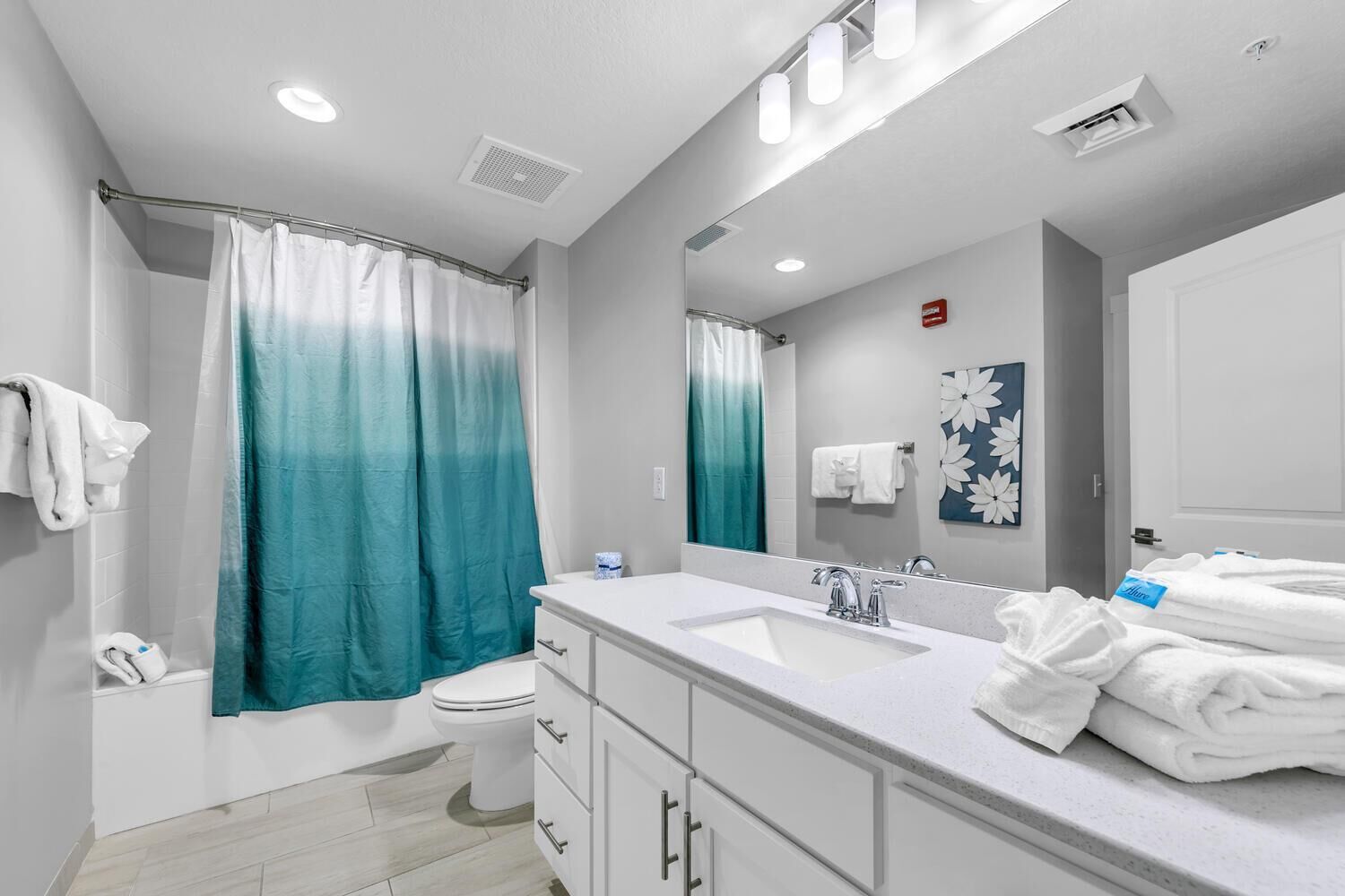 A modern bathroom with a shower, toilet, and a large vanity with a mirror.