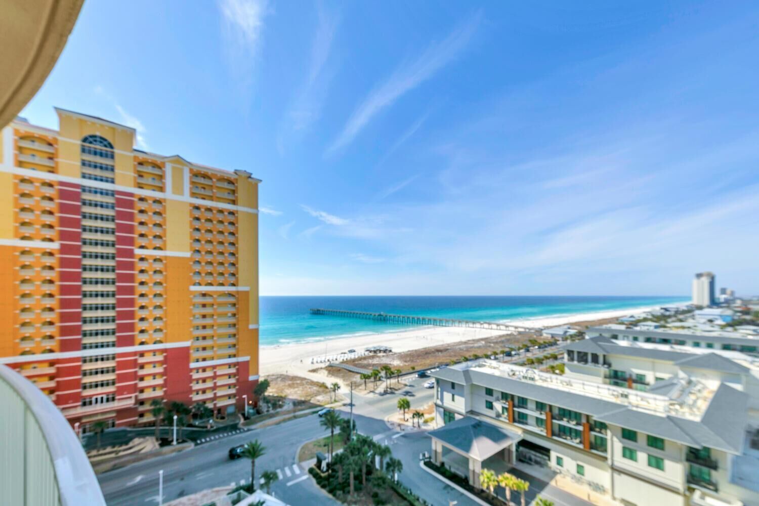 A high-rise hotel with a view of a beach and a pier.