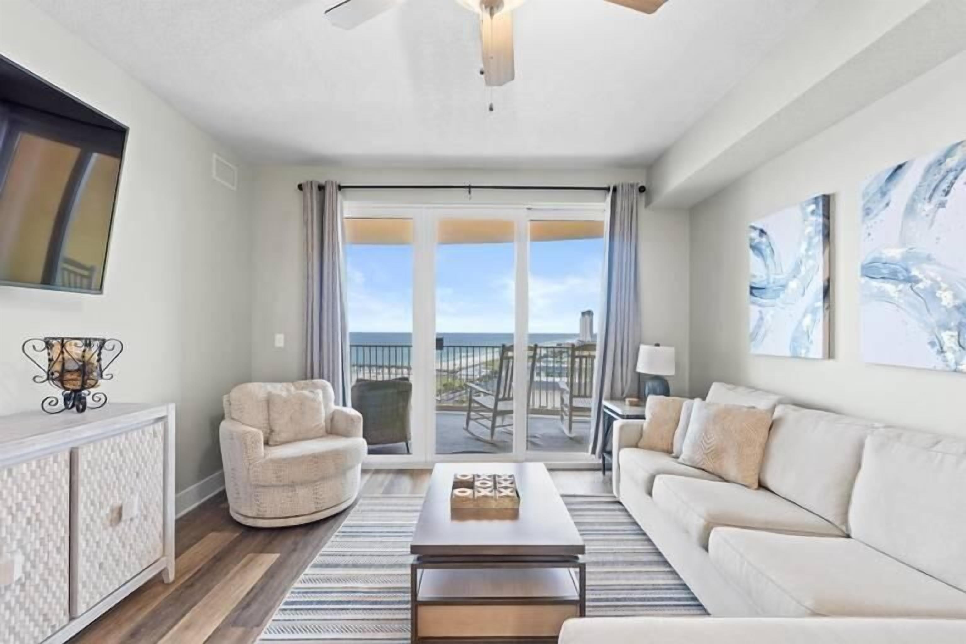 A living room with a sofa, armchair, coffee table, and a view of the outdoors through a sliding door.