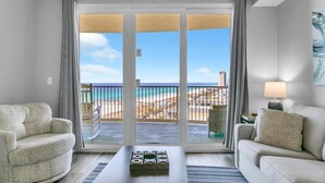 A hotel room with a balcony, two sofas, a coffee table, and a view of the beach and ocean. - Calypso 3-1107 (Panama City Beach)