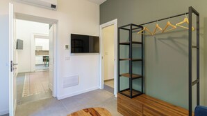 Un intérieur moderne avec un plancher en bois, un téléviseur fixé au mur et un portant à vêtements.