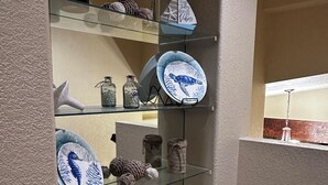 A display of decorative items including plates, glass jars, and a seahorse ornament on shelves.