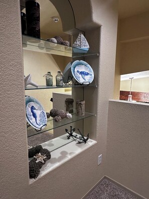 A display of decorative items including plates, glass jars, and a seahorse ornament on shelves.