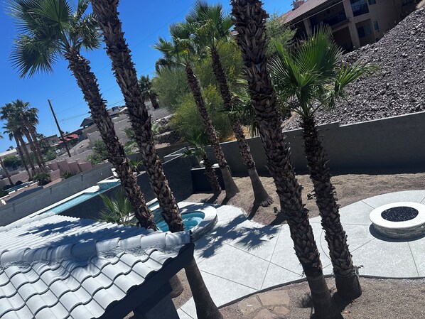 Un área de piscina con palmeras, un suelo de baldosas y un edificio al fondo.