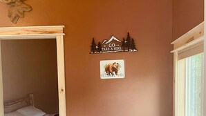 Une pièce confortable avec un lit, une chaise agrémentée d’un coussin coloré, une petite table en bois et une fenêtre.