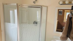 Une salle de bain avec une douche à parois de verre, un lavabo blanc et un miroir au-dessus.