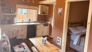 Un intérieur de chalet chaleureux comprenant un coin cuisine, un espace repas et un coin nuit.