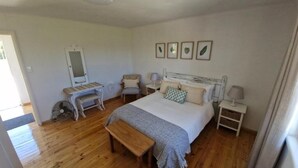 Une chambre à coucher comprenant un lit, des tables de chevet, un miroir, une chaise et un banc.