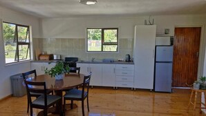 Une cuisine de taille réduite comprenant une table à manger, des chaises, un évier et un réfrigérateur.