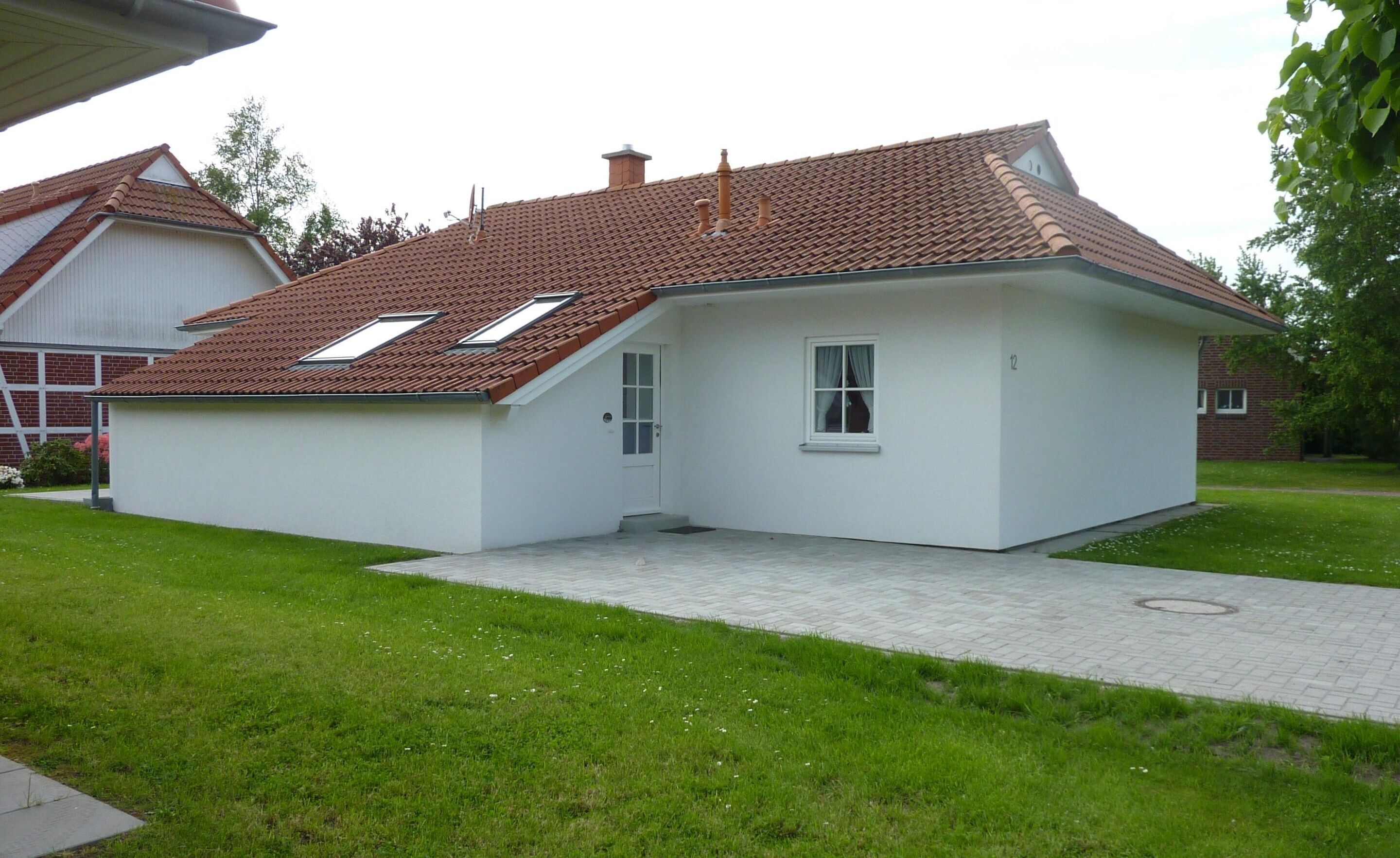 A single-story house with a tiled roof, a small porch, and a visible door.