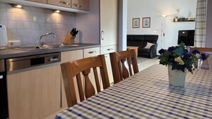 A modern kitchen with wooden cabinets, a stainless steel sink, and a dining area with a checkered tablecloth.
