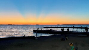 A beach with a pier extending into the water, people walking along the pier, and a sunset in the background. - Charming 4-bedroom house near the Lakeside pool & pickleball courts (Lakeside)