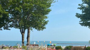 A pool with a wooden bench and flowers, a clear view of the sea, and a few sailboats. - Charming 4-bedroom house near the Lakeside pool & pickleball courts (Lakeside)