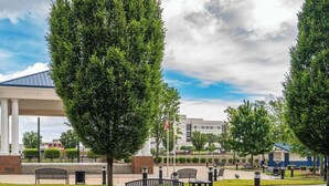 Ein gepflasterter Weg mit Bänken, einem Pavillon und einem Gebäude, auf dessen Säulen 'ROTARY' steht.