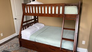 Ein Stockbett mit Holzbettgestell, ein gemustertes Teppich und eine Tür im Hintergrund.