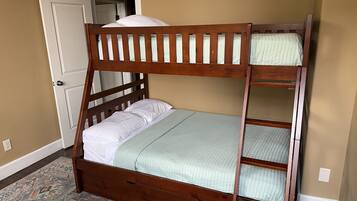 Un lit superposé avec une structure en bois, un tapis à motifs et une porte visible au fond.