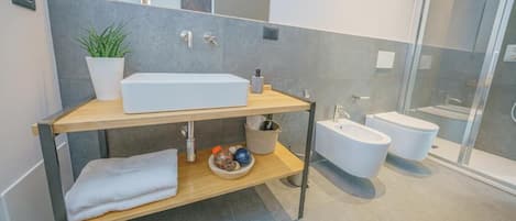 Um banheiro moderno com uma pia retangular grande, um bidê e um box de vidro.