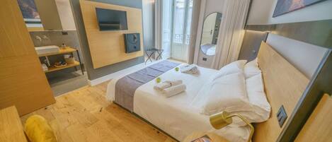 A modern hotel room with a bed, bedside table, and a TV mounted on the wall.