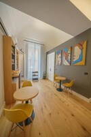 Un soggiorno moderno con zona pranzo, pavimento in legno e un'ampia finestra con tende leggere.