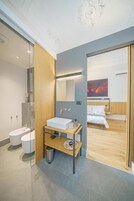 Un bagno moderno con cabina doccia in vetro, mobile lavabo in legno, lavandino bianco e zona doccia.