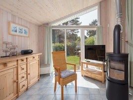 A cozy room with a wooden interior, a wicker chair, a TV, and a wood-burning stove.