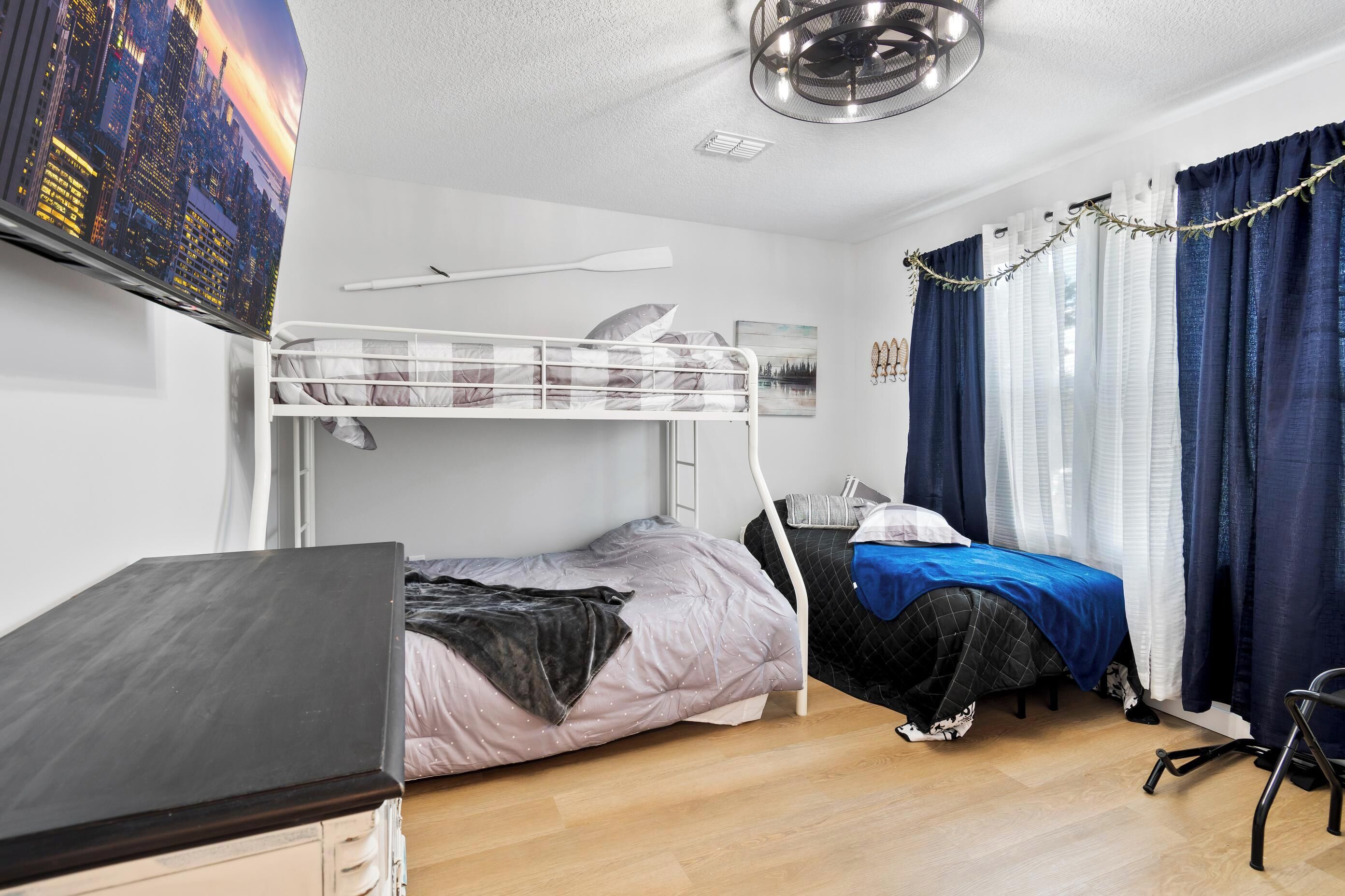 A bedroom with a bunk bed, a desk, and a chair.