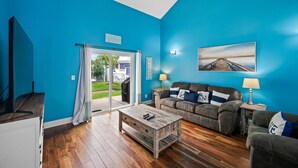 Een woonkamer met een blauwe wand, een houten salontafel, een bank en een schilderij.