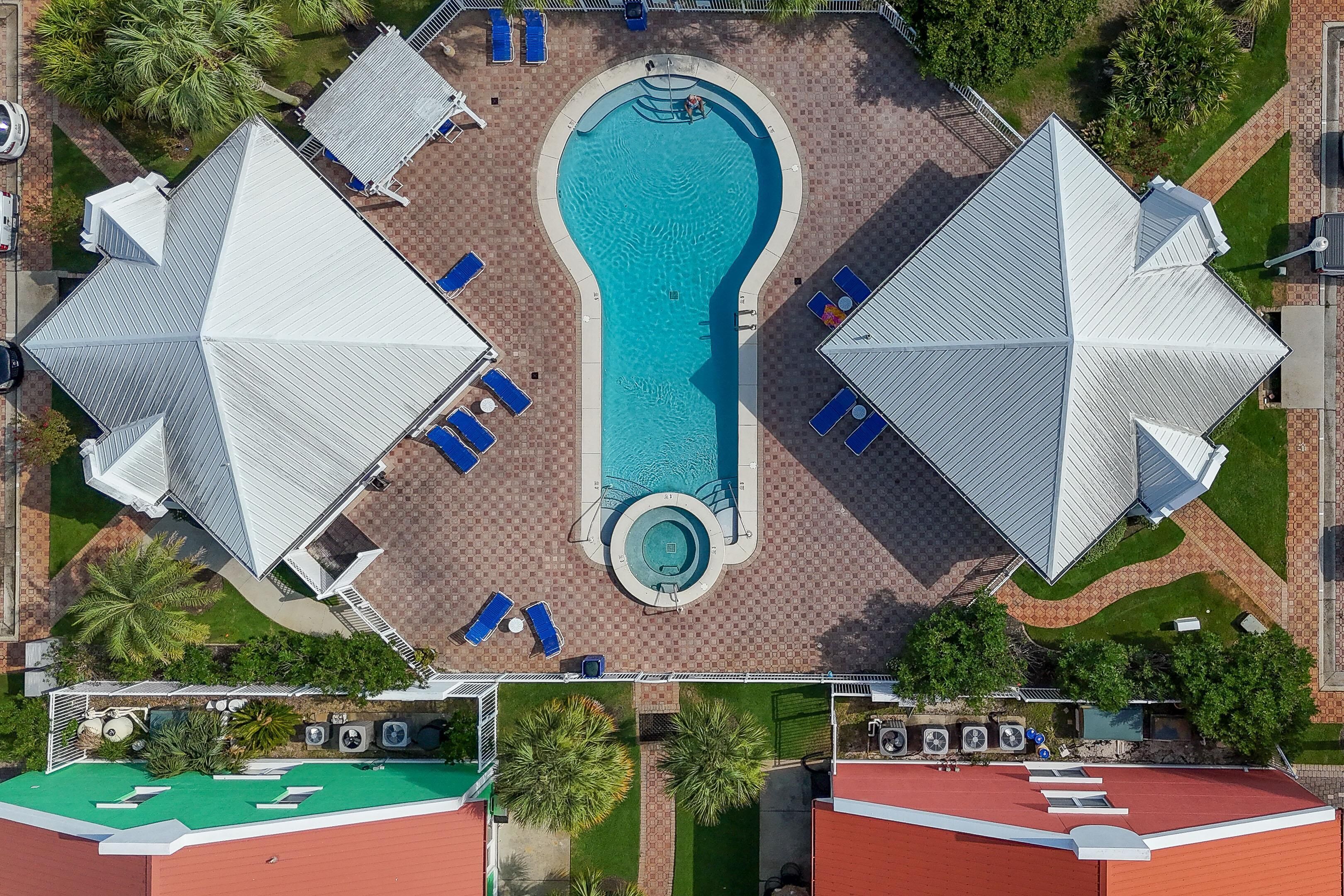 Vue aérienne d’un hôtel doté d’une piscine centrale, entourée d’espaces de détente et de zones extérieures abritées.