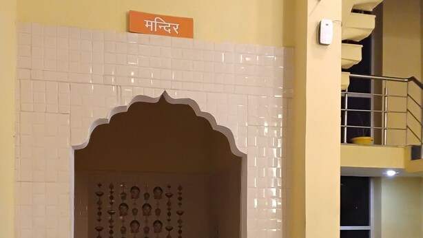 A room with a tiled wall, a staircase, and a sign with text. - Hotel Hansi (Hansi)