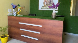 A reception desk with a Buddha statue, a vase with flowers, and a small Buddha figurine. - Hotel Hansi (Hansi)