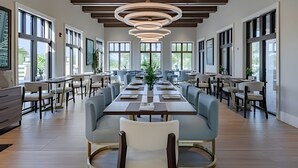 Un vaste espace dédié à la salle à manger, avec de longues tables et des chaises, de grandes fenêtres et un design moderne au niveau du plafond.