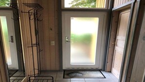 A narrow hallway with a frosted glass door, a metal rack, and a tiled floor. - Ferienhaus mit Sauna im Ferienpark Mirow (Mirow)
