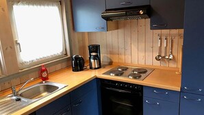 A compact kitchen with a stove, oven, and a coffee maker on the counter. - Ferienhaus mit Sauna im Ferienpark Mirow (Mirow)