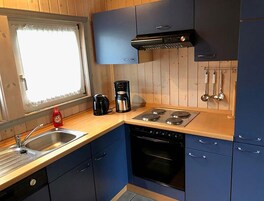 Una cocina compacta con estufa, horno y cafetera en la encimera.