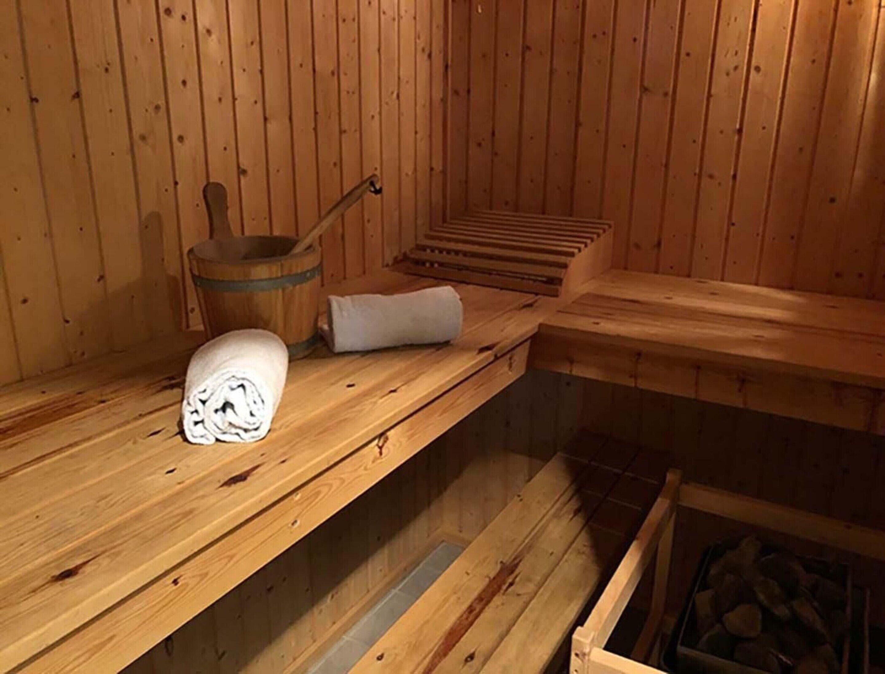 A wooden sauna with benches, a towel, and a bucket.